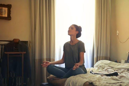 A woman meditating on her bed